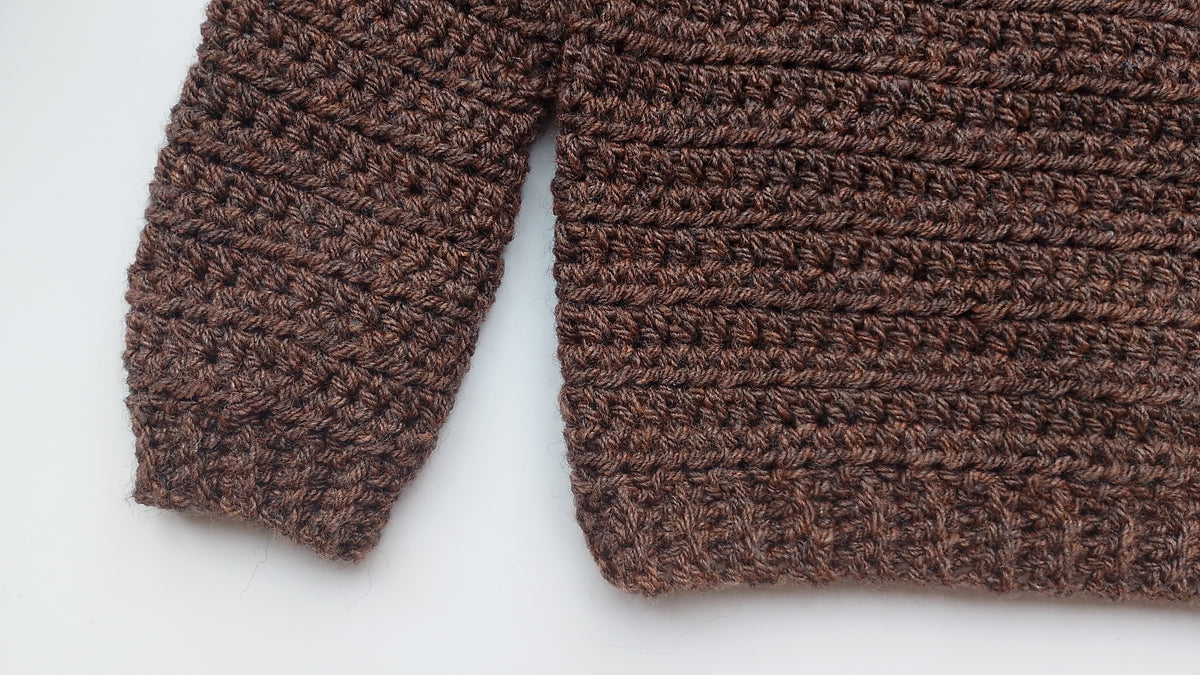 Close up of crochet stitches used in crocheting a chestnut brown pullover for babies and children.